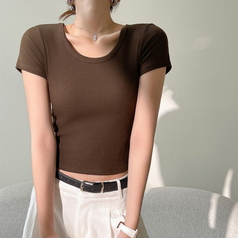 A model posing in a brown slim fit cotton tee, styled with white pants and a black belt, showcasing a fashionable and comfortable option for femboy outfits in femboy fashion.