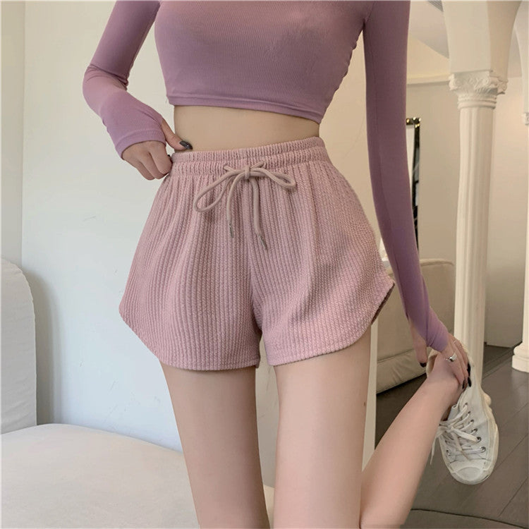 Model wearing soft pink high-waist yoga shorts paired with a cropped purple long-sleeve top, highlighting trendy femboy fashion and clothes.