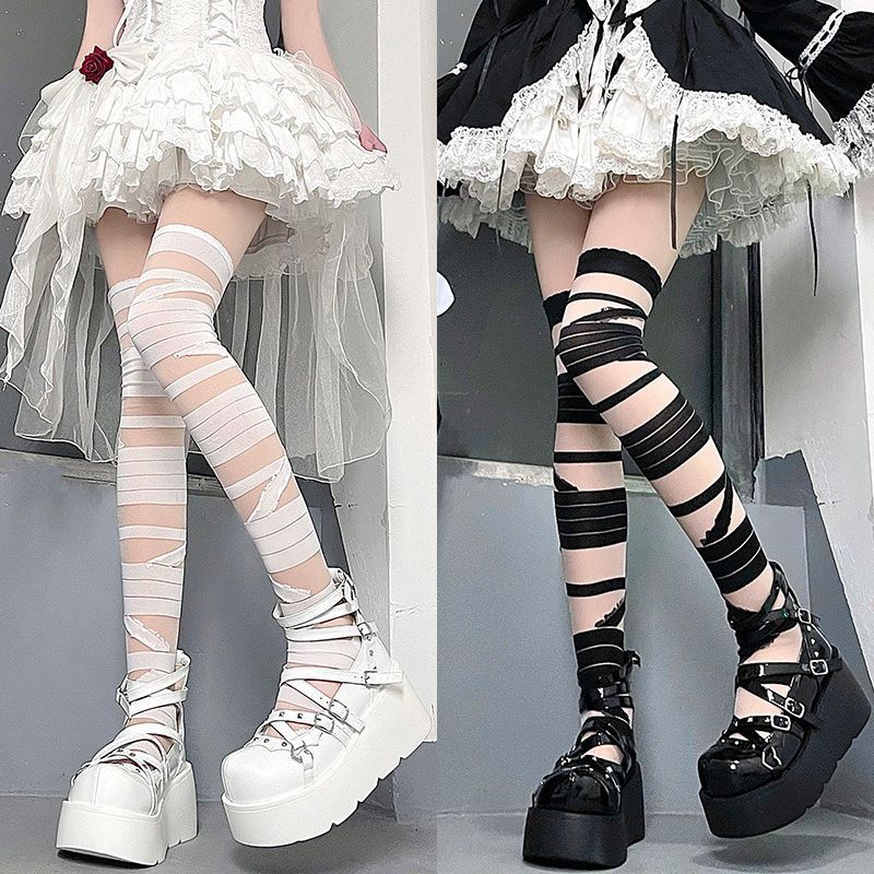 White and black strappy over-the-knee socks styled with platform shoes and layered outfit, soft aesthetic femboy legwear