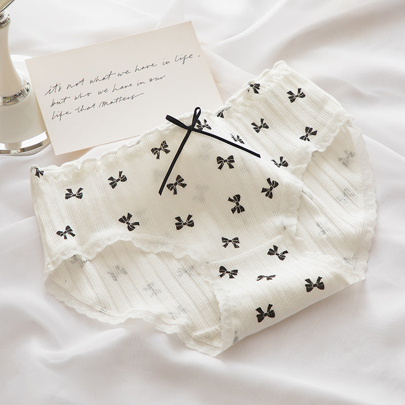 Close-up of white Lolita Bowknot Panties adorned with black bow prints and scalloped lace edges, captured from a top-down angle, ideal for a femboy wardrobe.