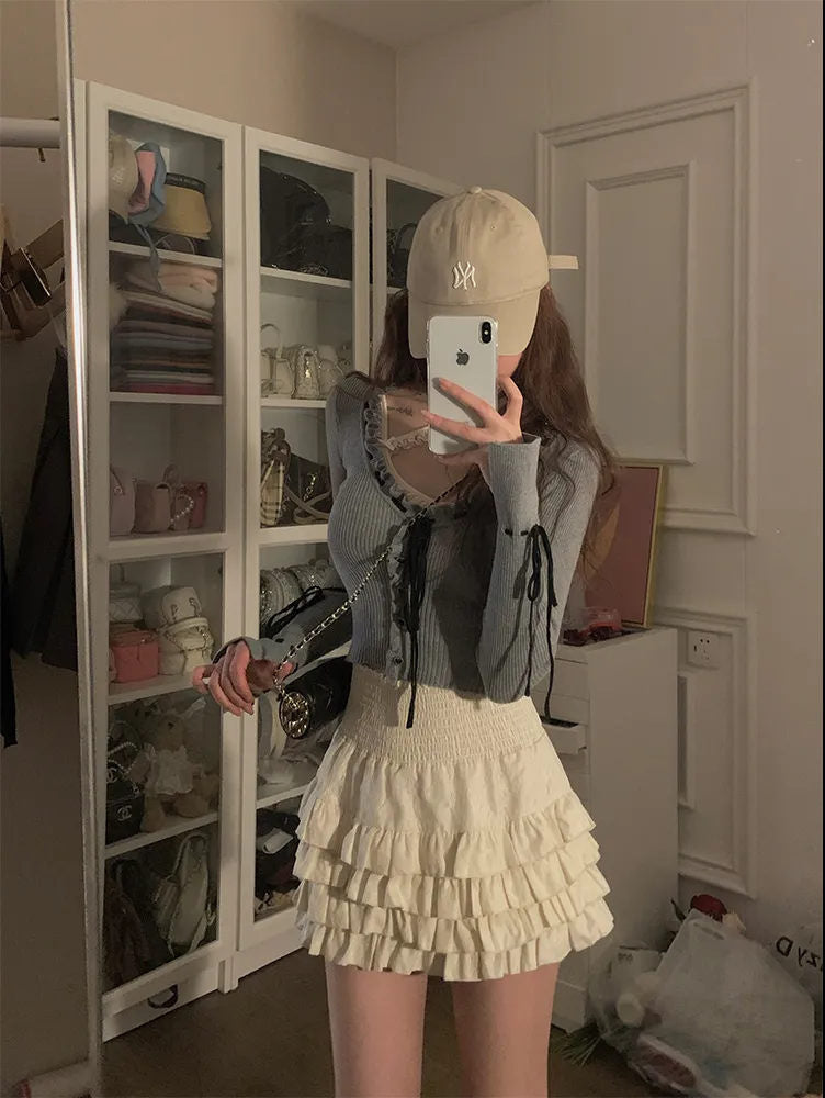 Mirror selfie of a white High-Waist Cake Skirt paired with a blue lace-up top. Taken indoors with a stylish closet backdrop, perfect for showcasing elegant femboy clothes and femboy fashion.