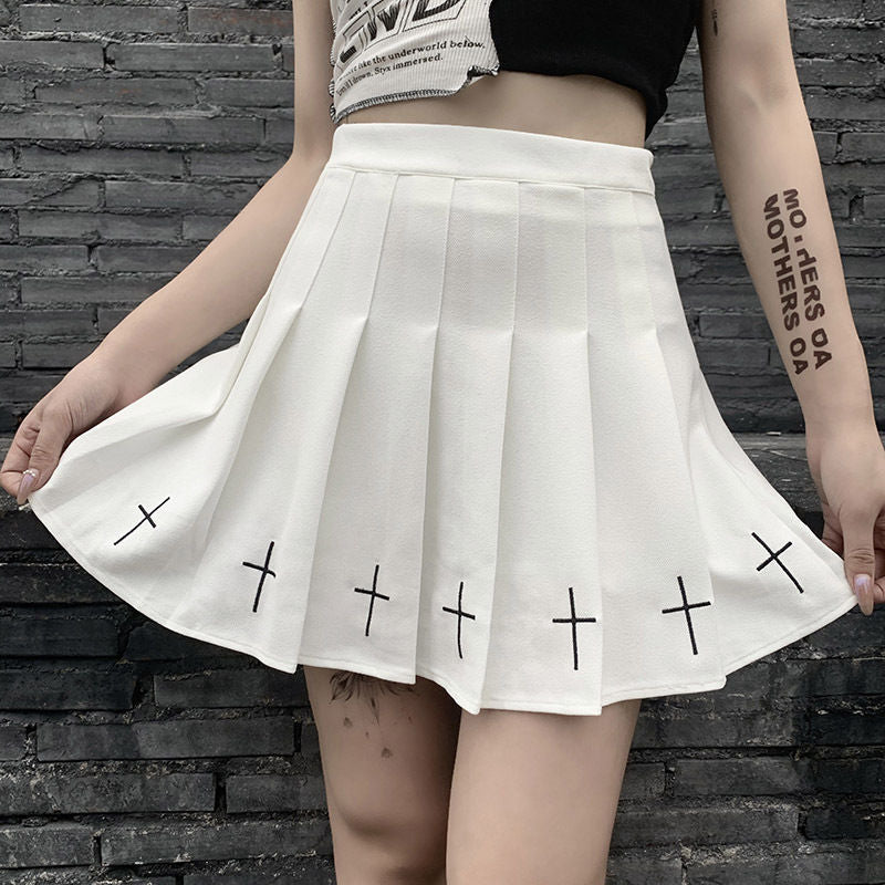 White gothic pleated skirt with cross detailing in soft edgy femboy fashion look, flowing silhouette styled with crop top and minimal accessories