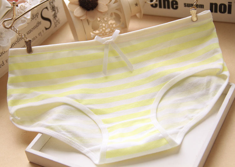 Soft yellow and white striped panties with a bow accent, shown on a beige surface. Perfect for femboy fashion and casual femboy clothes.